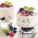 two-bowls-of-yogurt-on-a-wooden-table-topped-with-berries